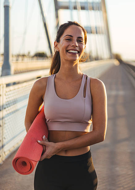 istock Smiling Woman With Yoga Mat Standing Outdoors During Sunset 2217888304