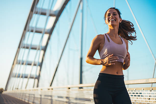 istock Smiling Woman Jogging on a Bridge Under a Clear Sky at Sunset 2217888305