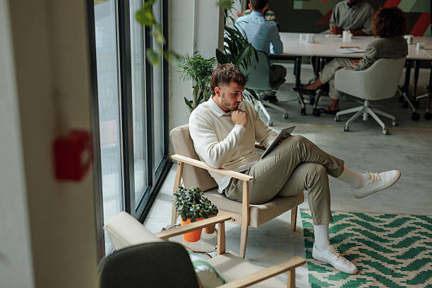 istock Businessman using tablet in modern office with colleagues working in background 2217889162