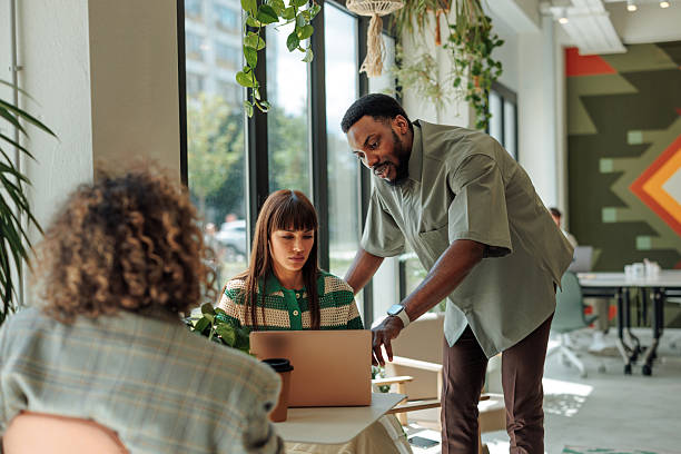 istock Manager guiding his employees working on a laptop in the office 2217889228