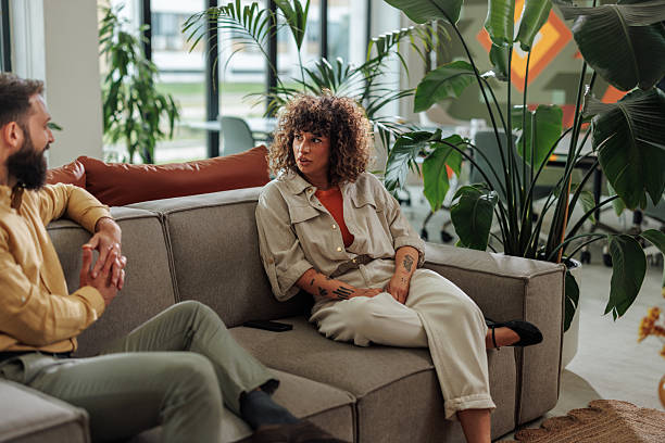 istock Colleagues having a conversation sitting on a sofa in a modern office 2217889274