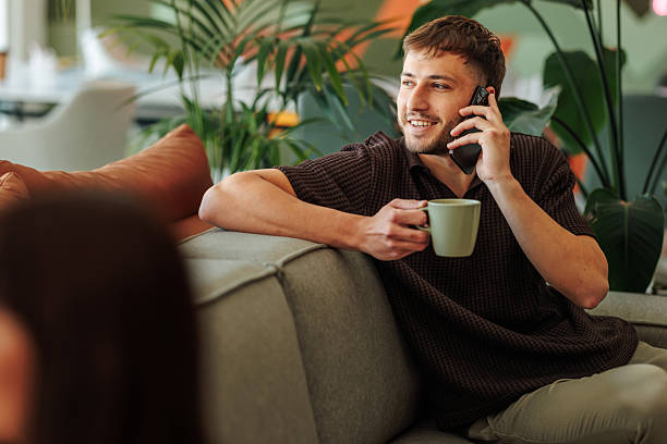 istock Young man talking on the phone and drinking coffee in a modern office 2217889297