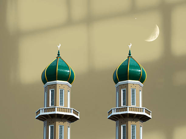 Minimalist composition focusing on three slender mosque minarets rising into a pale sky. The clean background emphasizes vertical lines, architectural form, and the symbolic presence of Islamic religious structures.