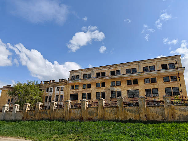 istock historic abandoned building with weathered facade and overgrown yard under blue sky. closeup. 2217897701