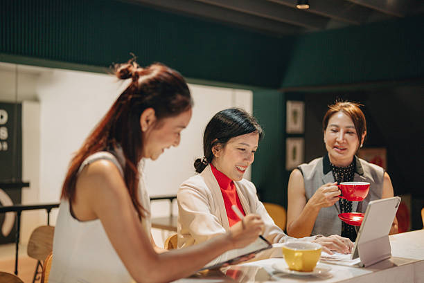 istock Side view of group of smart business colleagues drinking coffee, checking data on laptops and sharing documents in a collaborative workspace. 2217903105