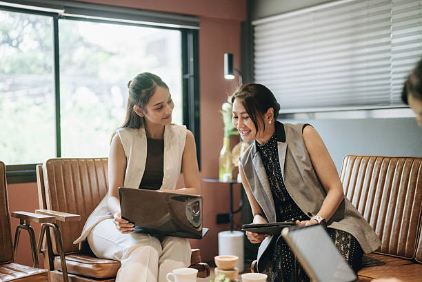 istock Relaxed Asian team analyzes content on laptops, chats and works intently in a trendy restaurant. 2217903199