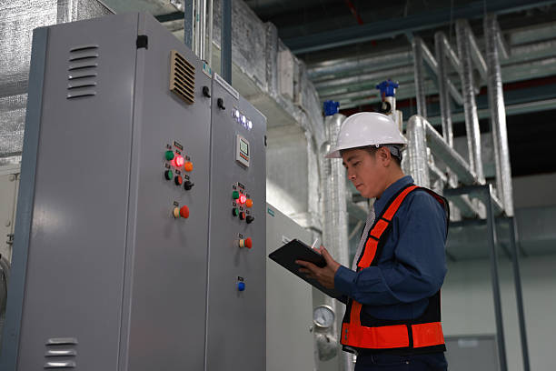 istock A Man electrical engineer in red safety vest and white hardhat check control switchgear or MDB and record to laptop 2217910438