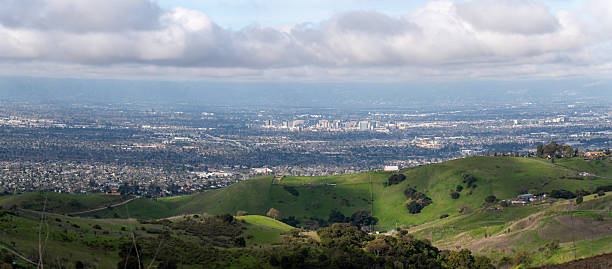 istock A panoramic view of a city from rolling green hills under a cloudy sky. 2217915812