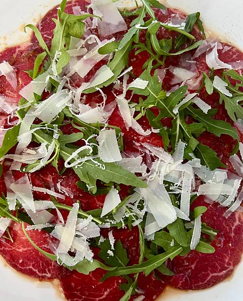 Classic Carpaccio, sliced raw beef mean with arugula and Parmesan