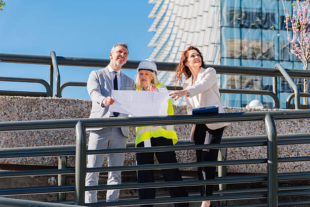 istock Professional architects reviewing blueprint near sleek architectural structure, discussing complex building design with collaborative teamwork in contemporary urban environment 2217927491