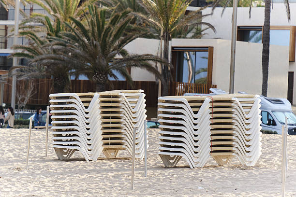 Straw beach umbrellas and wooden sunbeds are perfectly arranged on a sandy beach, creating a serene and inviting atmosphere for relaxation by the sea