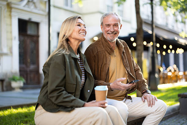 istock Smiling senior couple enjoying coffee and using smartphone outdoors 2217941049
