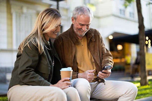 istock Senior couple using smartphone and drinking coffee outdoors 2217941050