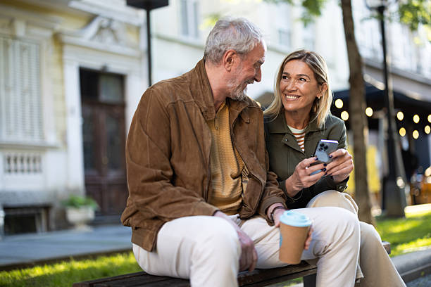 istock Senior couple using mobile phone and drinking coffee outdoors 2217941060