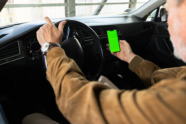 istock Mature man driving car while looking at green screen smartphone 2217941180