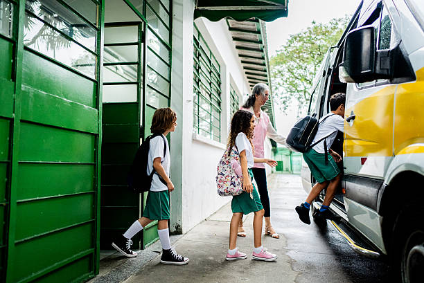 School monitor helping students enter the school van