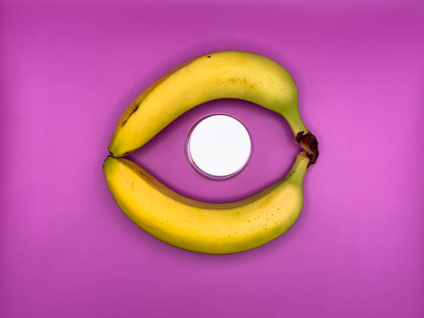 Two bright yellow bananas create a circle in which lies a jar with a white lid for medicines, top view, in the center of the image. High quality photo