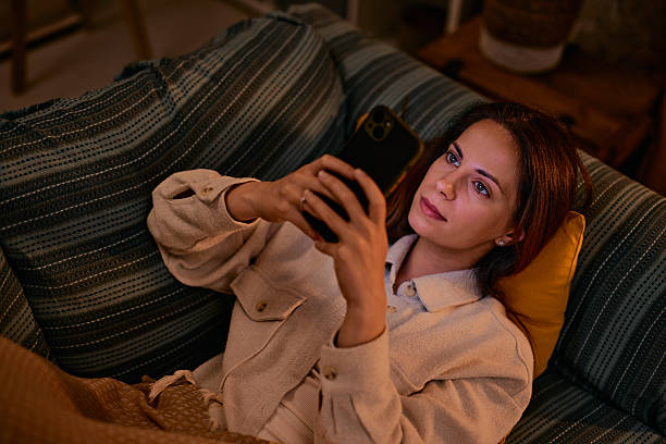 istock Young woman relaxing on the sofa using her smartphone in the evening 2217946293