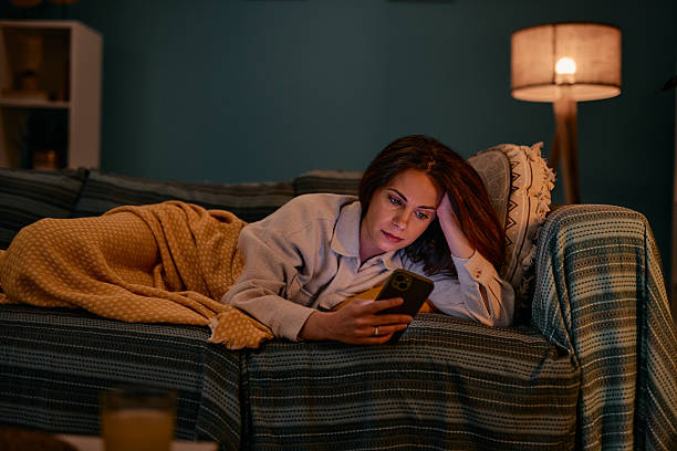 istock Young woman relaxing on the sofa using mobile phone at night 2217946398