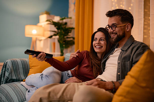 istock Couple relaxing on sofa, watching television and changing channels with remote control 2217946604