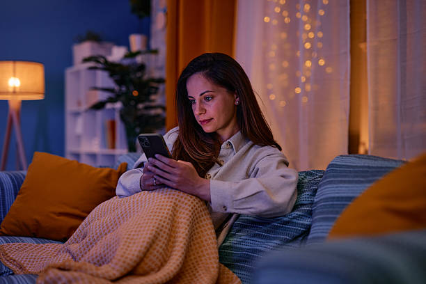 istock Woman relaxing on the sofa using her smartphone in the evening 2217946668