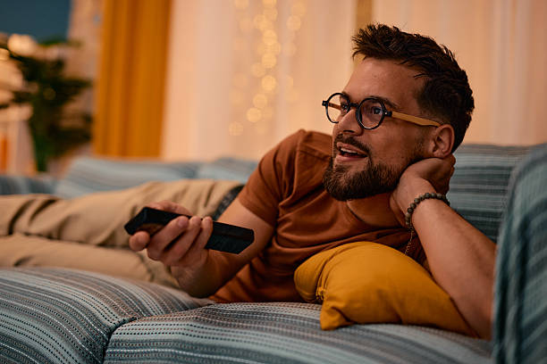 Young man relaxing on sofa watching television at home