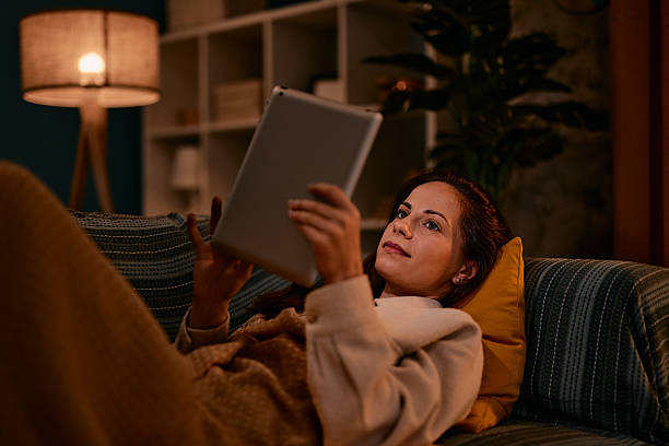 istock Woman relaxing on sofa using digital tablet at night 2217946899
