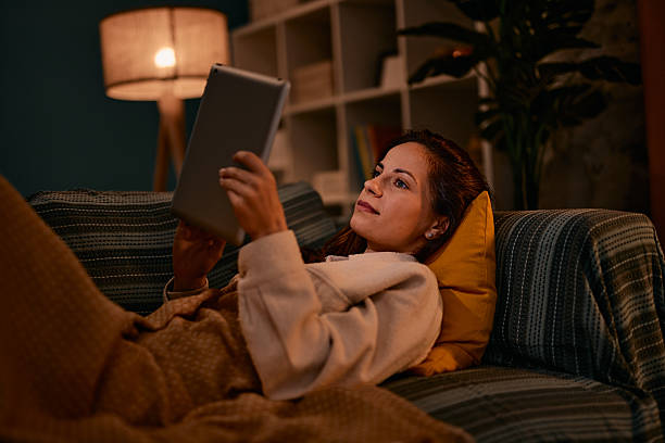 istock Woman relaxing on sofa using digital tablet at night 2217946900