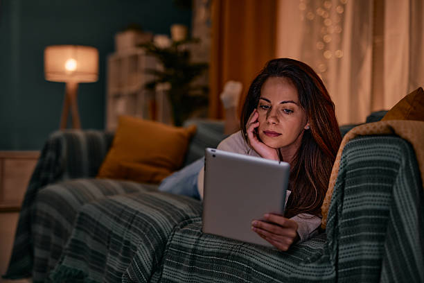 istock Woman relaxing on the sofa using a tablet in the evening 2217946923