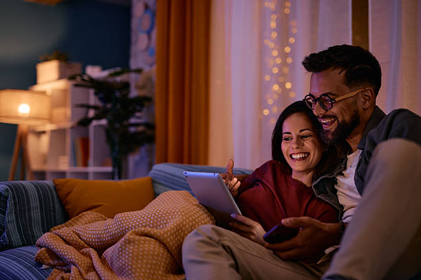 istock Happy couple relaxing on sofa using digital tablet at night 2217946938