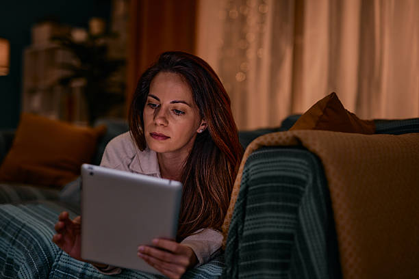 istock Woman relaxing on the sofa reading on a digital tablet at night 2217947015