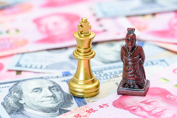 istock US-China trade relations, geopolitical tensions, tariff war resolution : A king chess piece paired with a Chinese emperor warrior figure rests on a backdrop of US dollar and Chinese yuan banknotes. 2217948910