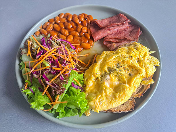 American Breakfast With Sourdough Bread, Scrambled Egg, Beef Bacon, Baked Beans And Mix Greens. Food Menu.