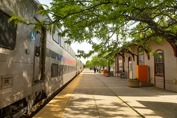 Ramsey, New Jersey, USA - May 12, 2025: In the afternoon a NJ Transit train departs from its scheduled stop along its route. People exiting can be seen in the distance.