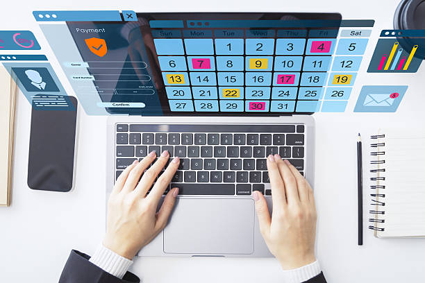 istock Hands typing on laptop with digital calendar and virtual interface on office desk from top view perspective. 2217957664