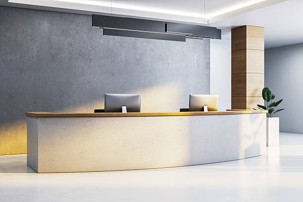 istock Modern reception desk with dual monitors in minimalist office interior featuring wood and concrete elements under ceiling lights and clean background. 3D Rendering 2217957798