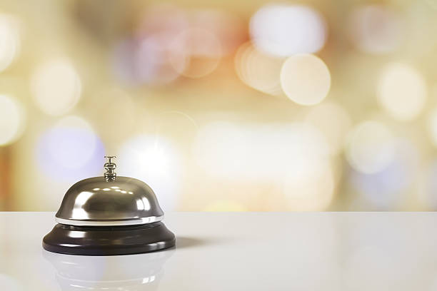 istock Hotel service bell on glossy white counter with glowing bokeh light background in soft pastel tones. 3D Rendering. 3D Rendering 2217957883