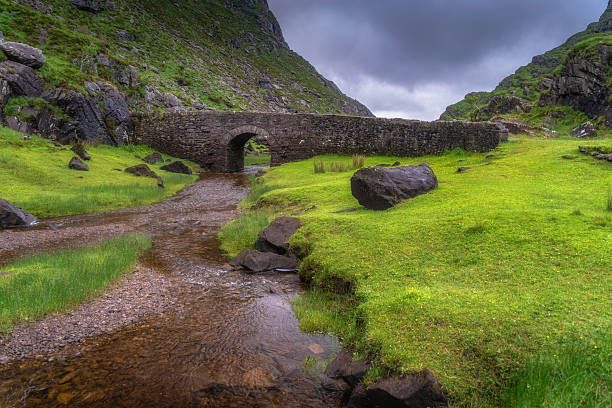istock Serene and Picturesque Landscapes Ancient Stone Bridge Gracefully Arching Over a Tranquil Stream in Lush Green Valleys 2217964502