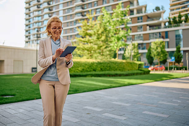 istock Smiling businesswoman using digital tablet while walking in the city 2217966786