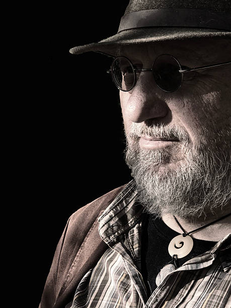 Portrait of Thoughtful Man with Hat and Glasses looking at camera.