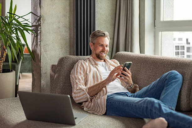 istock Casual man using phone in modern bright living room. 2217971895