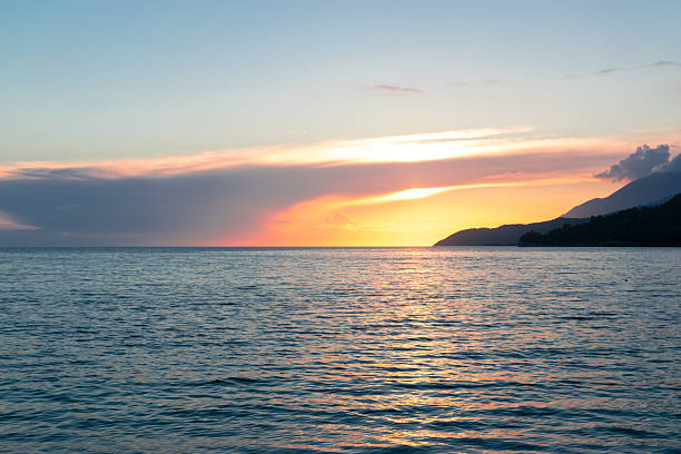 Dramatic sunset sky over the Mediterranean Sea with mountain silhouettes along the Cyprus coastline. Vivid colors and natural contrast create a striking seascape.