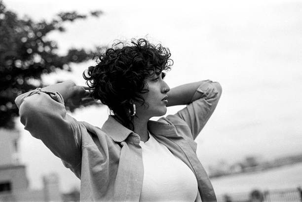 istock Young woman holding her curly hair with hands outdoors, grainy analog effect 2217981984
