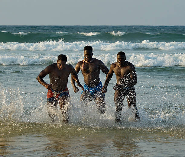 Dakar. Senegal. October 13, 2021. Muscular wrestlers ritually run out of the sea to the sandy shore with an abundance of water spray after the end of the Laamb wrestling competition.