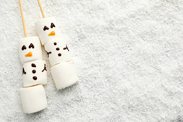 istock Cute snowmen made of marshmallows on artificial snow, top view. Space for text 2217988650