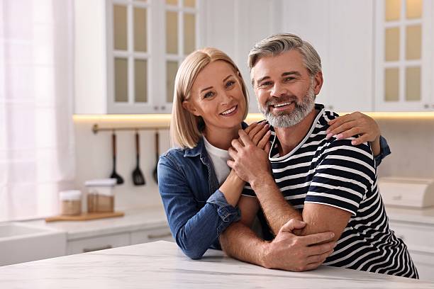 istock Happy middle aged couple at white marble table in kitchen 2217990932