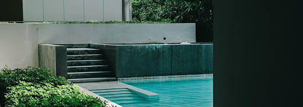 istock Swimming Pool concept. Modern Minimalist Swimming Pool with Steps Surrounded by Lush Greenery and Calm Water Reflections 2217991205