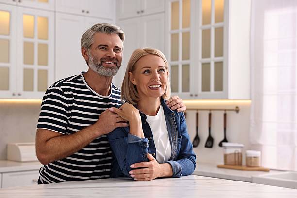istock Happy middle aged couple at white marble table in kitchen 2217991792