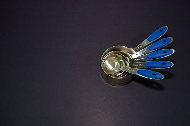 Measuring cups laying together on black background close up view