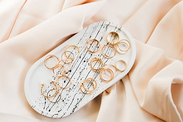 istock Elegant gold rings arranged on a decorative plate atop silky fabric 2217995500